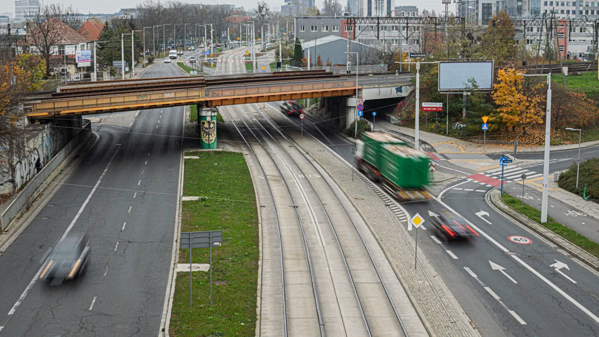Busy urban highway underpass with blurred motion vehicles and nearby buildings.